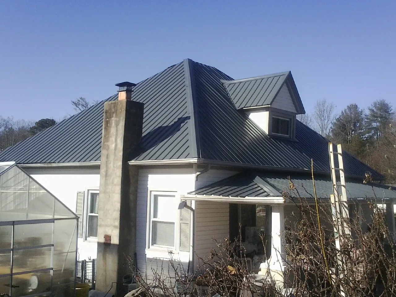 Dark blue standing seam metal roof on a white farmhouse with dormer — Slate & Tile Roof Repair by Roofing Brothers in Port Deposit