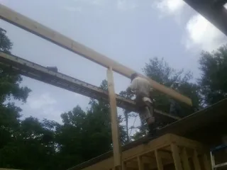 Carpenter setting a ridge beam over a new addition frame — Ice Dam Removal by Roofing Brothers in Port Deposit