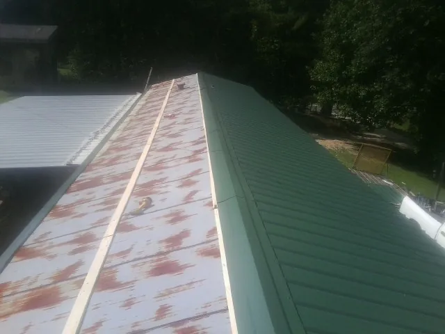 Old rusted panels beside newly installed green metal roofing — Wind Damage Roof Repair by Roofing Brothers in Port Deposit