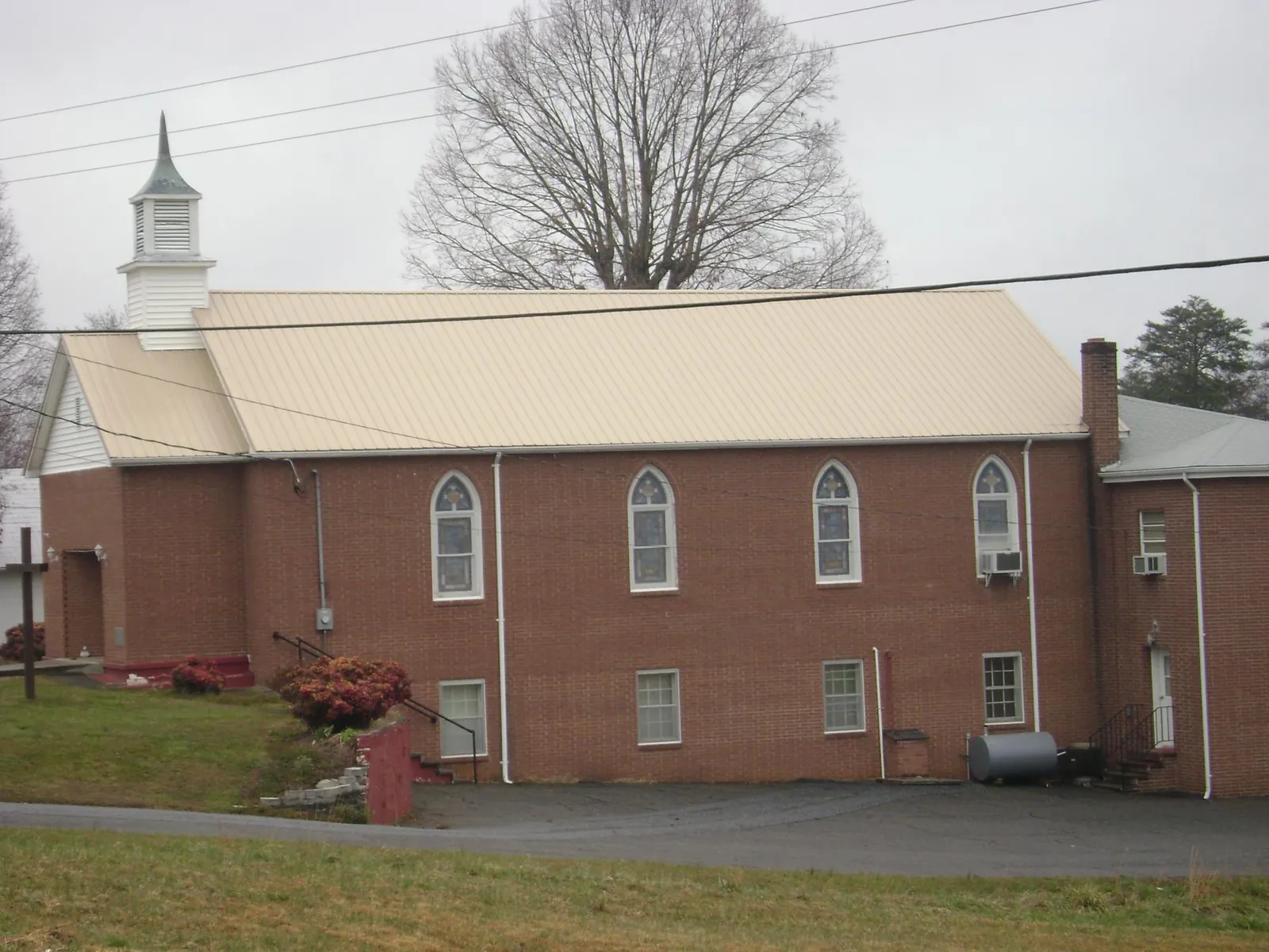 New tan metal roof on a brick church with a white steeple in Port Deposit
