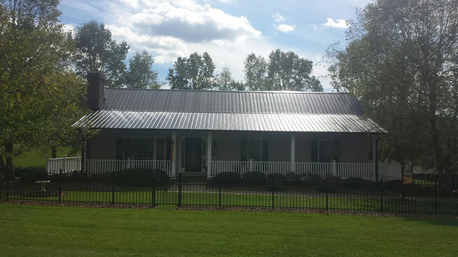 Gray metal roof on a brick ranch with a full width front porch — Gutter Guard Installation work by our crew in Port Deposit