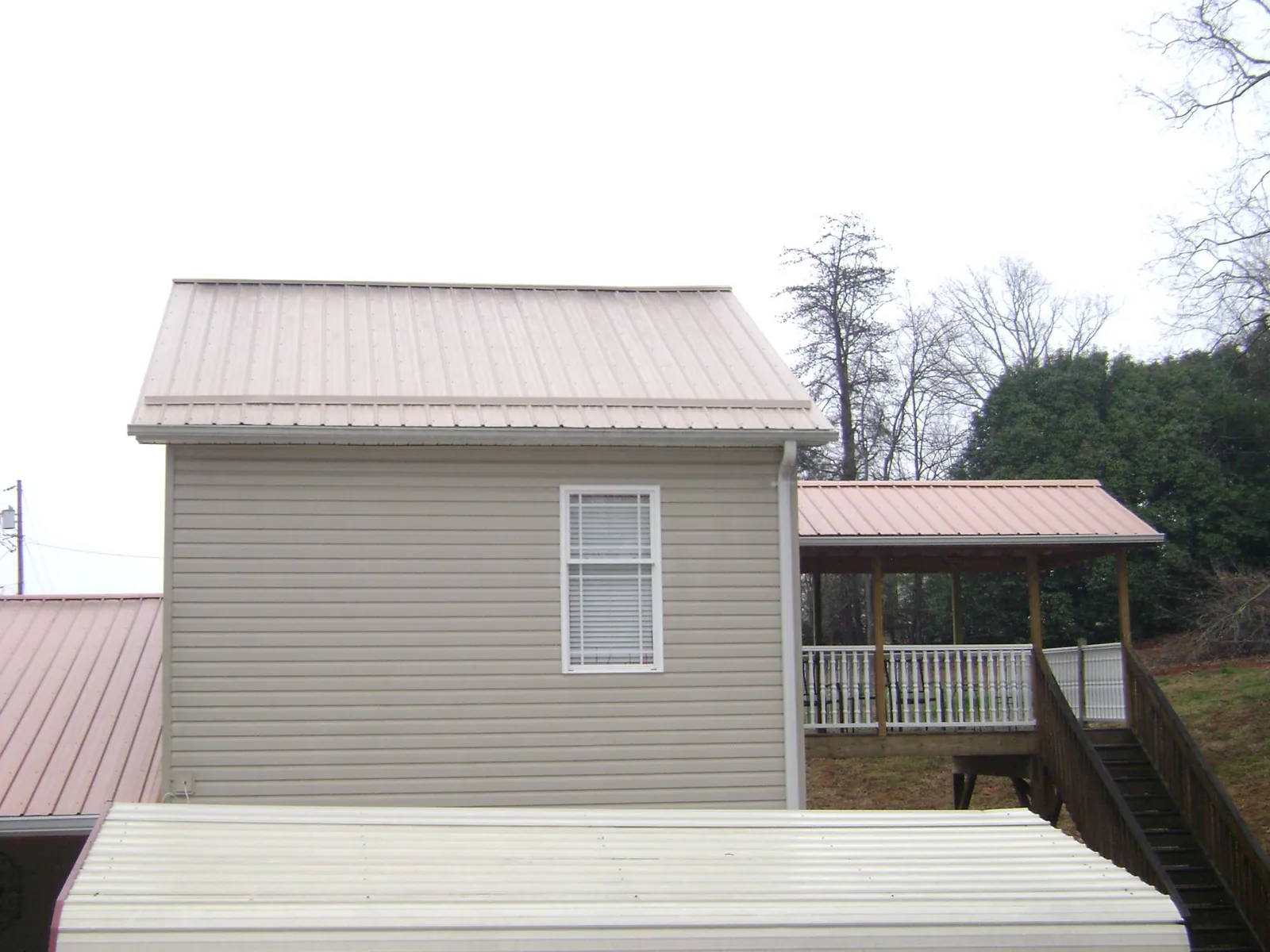 Tan metal roofs on a two story addition and attached porch, from a Roof Replacement job in Port Deposit